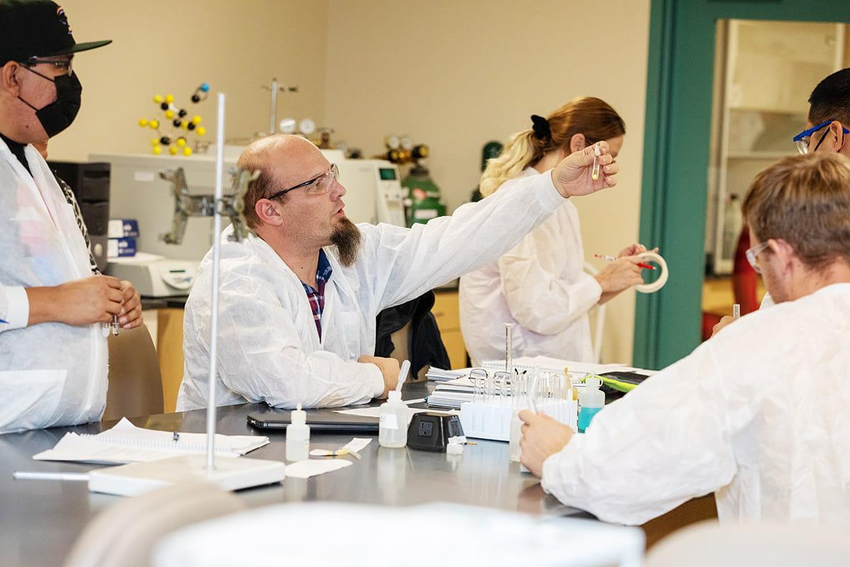 Chemistry students in a Lab working with test tubes and collaborating with instructor